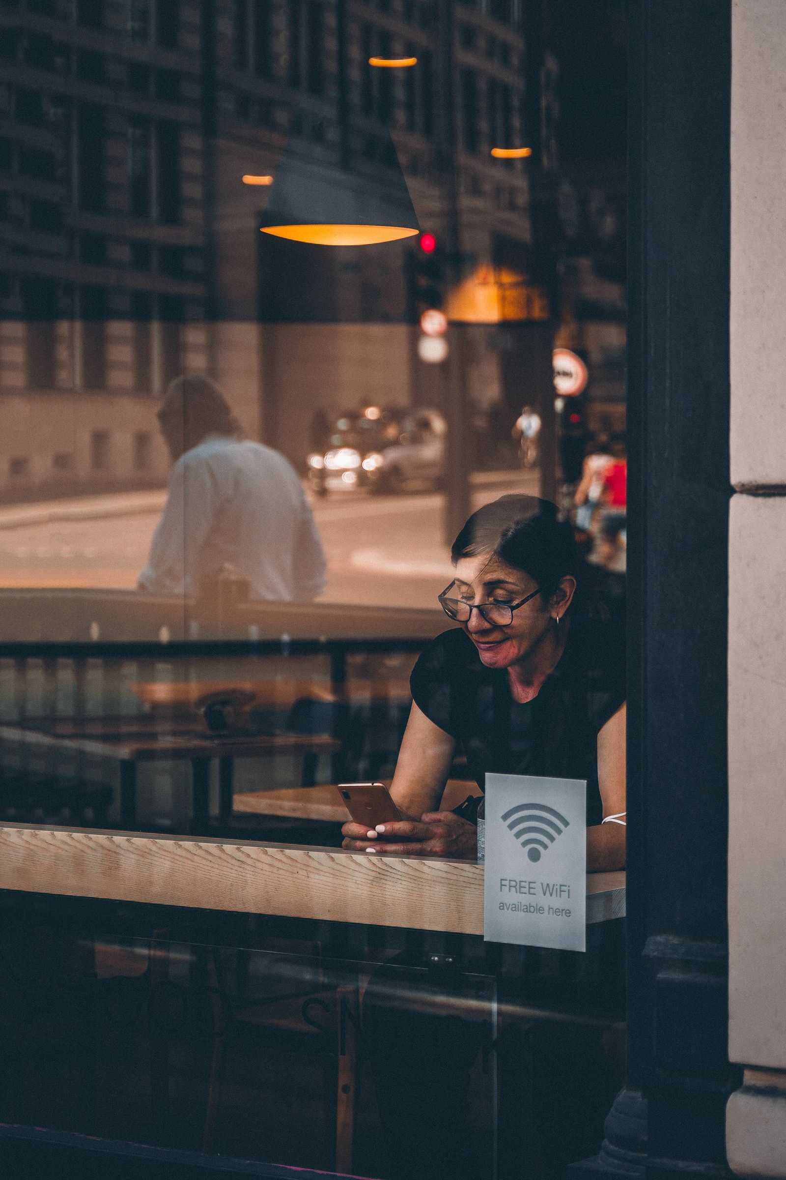 A woman using her phone behind the window of a café A woman using her phone behind the window of a café