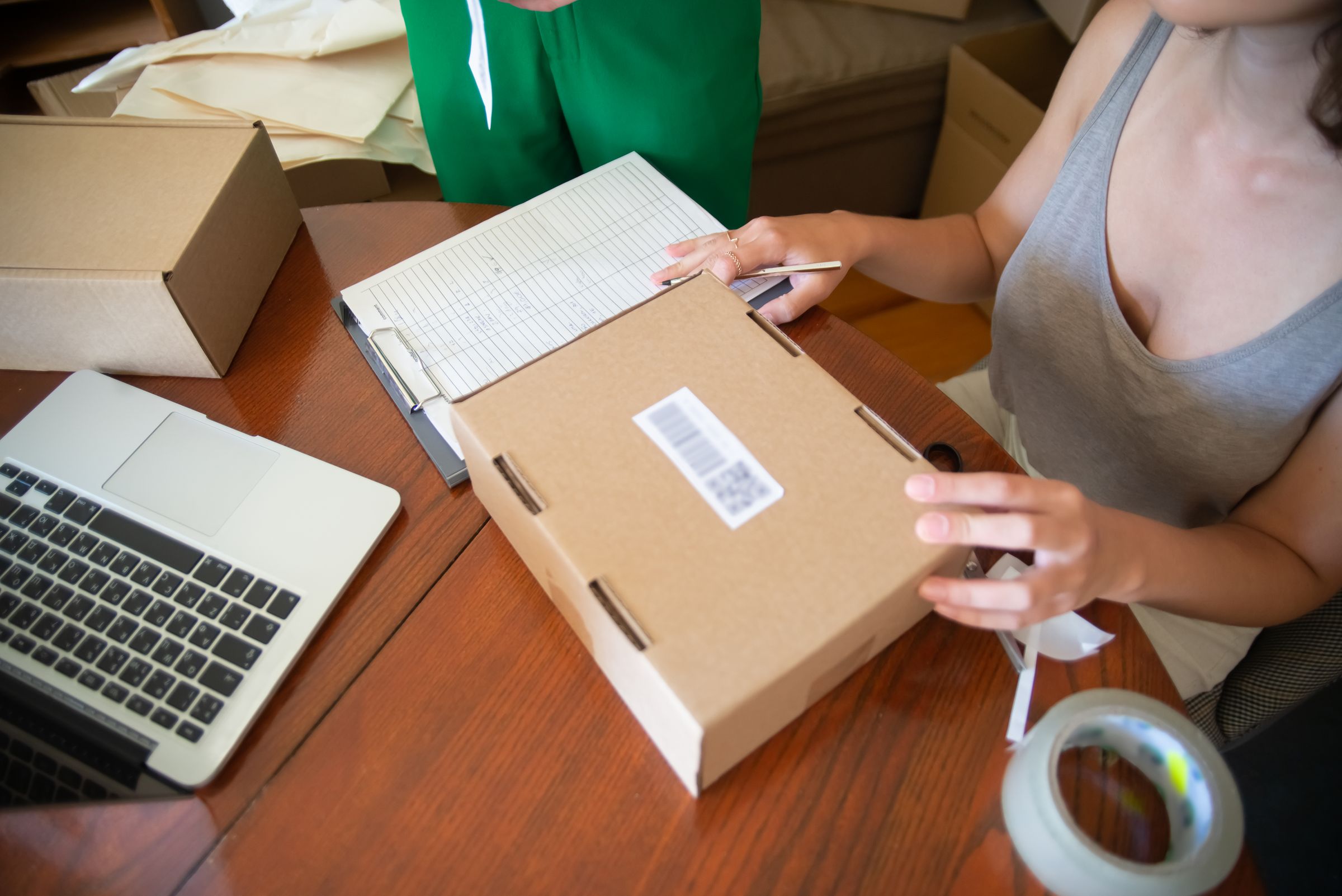 Hands preparing an online order beside a laptop Hands preparing an online order beside a laptop